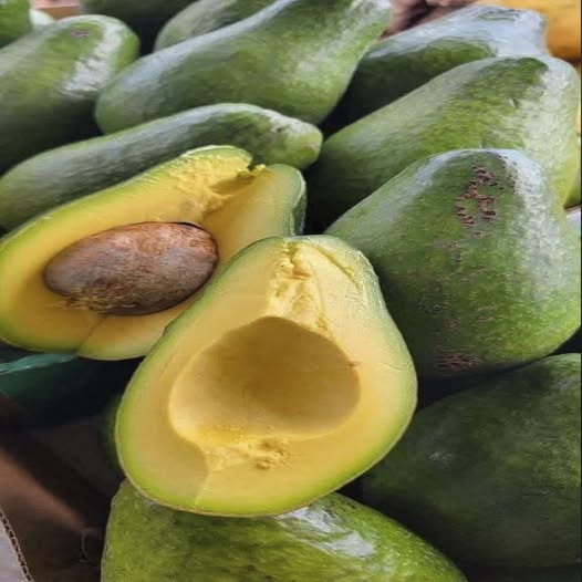 Varios aguacates frescos, incluyendo uno partido por la mitad